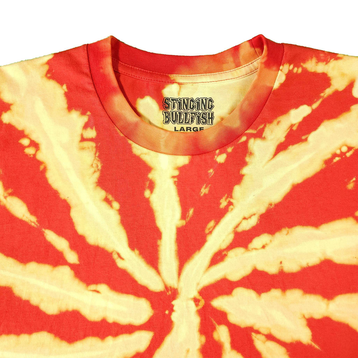 Tie-dye T-shirt close-up: red crewneck with cream spiral rays and chest logo.