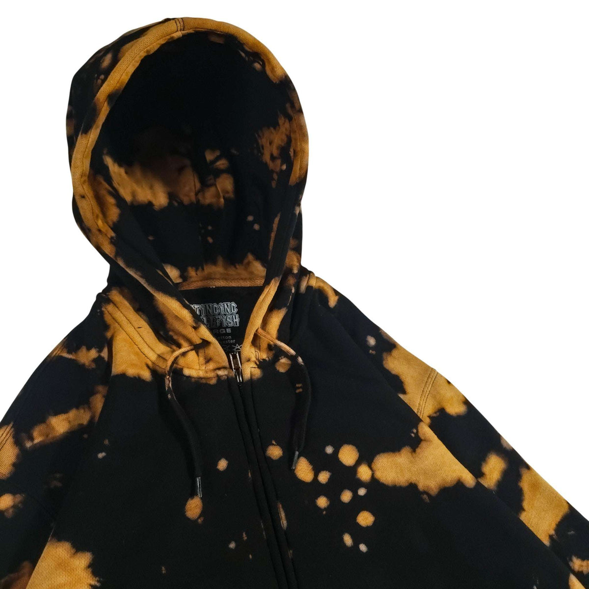 Zip hoodie close-up: black base with tan/gold bleach patterns; drawstring hood and zipper