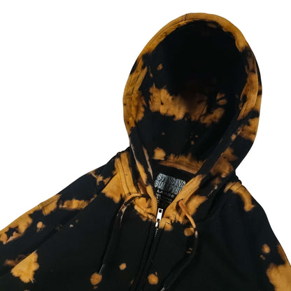 Black zip hoodie with tan/gold blotchy bleach print; hood drawstrings and zipper pull