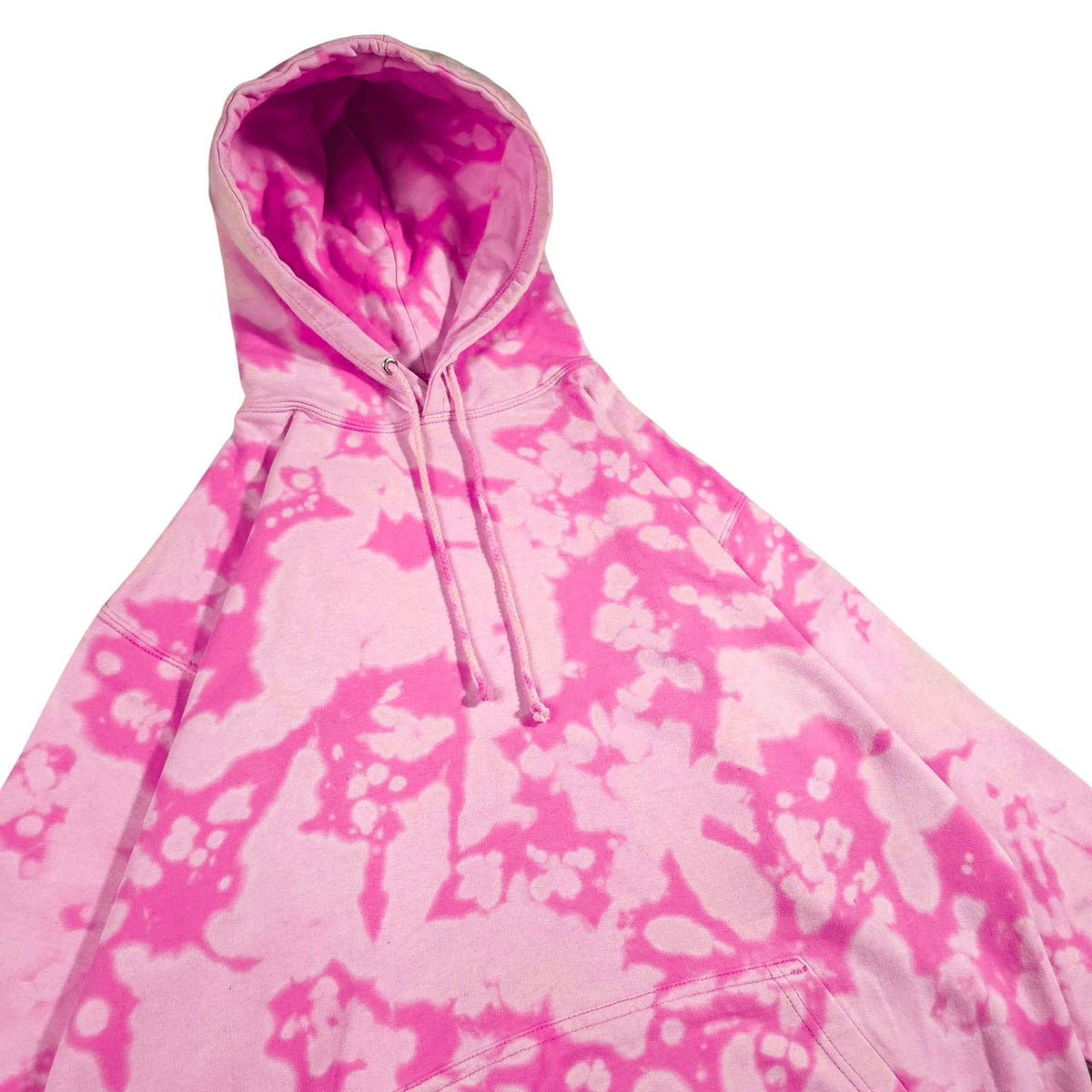 Pink bleach-dyed camo hoodie angled view with hood, drawstrings, and front pocket