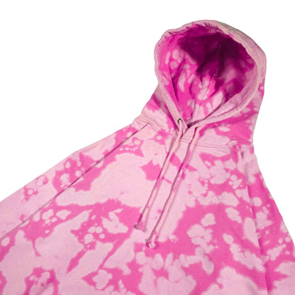 Pink bleach-dyed camo hoodie close-up with hood and drawstring cords, front pocket top