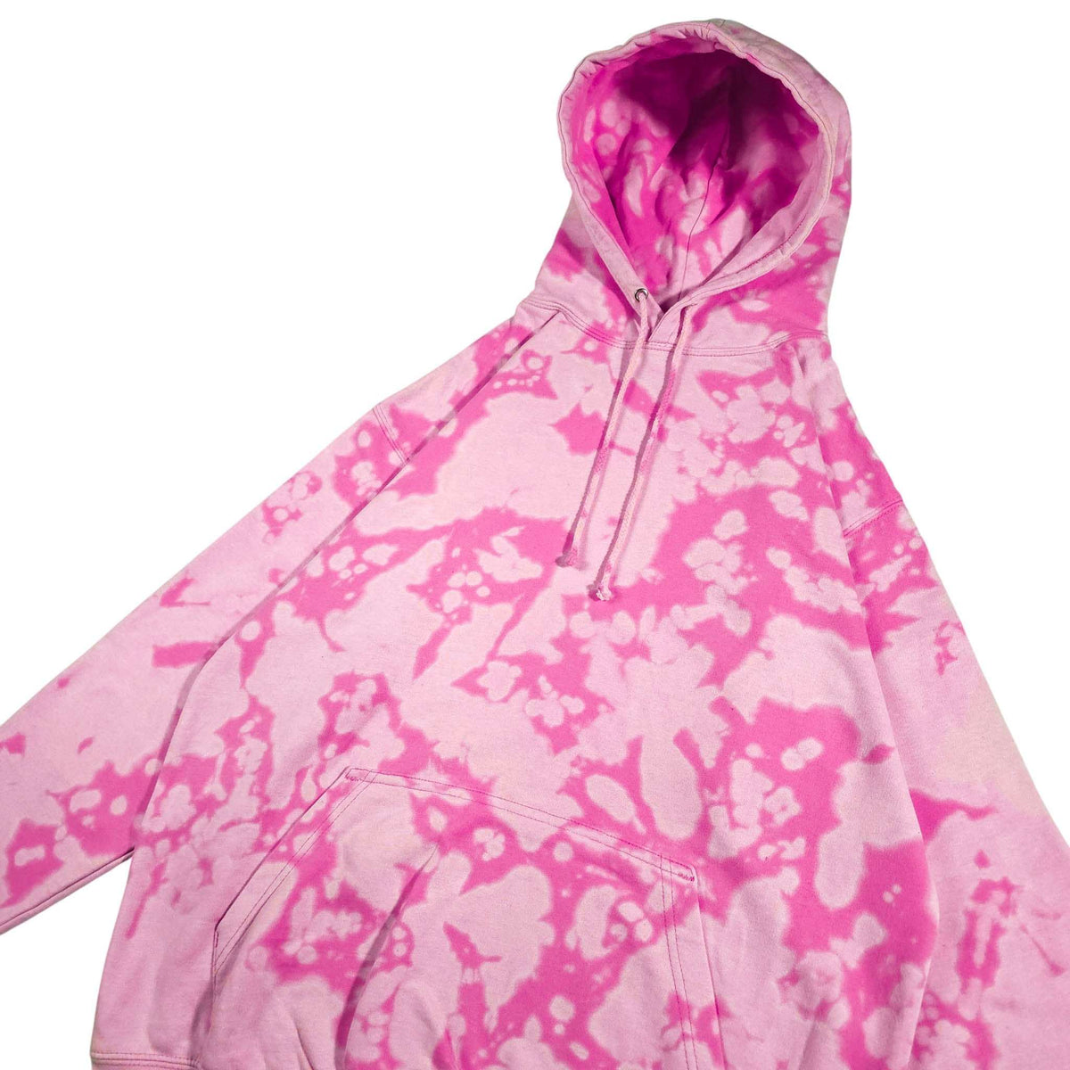 Pink bleach-dyed camo hoodie angled view with hood, drawstrings, and ribbed cuffs