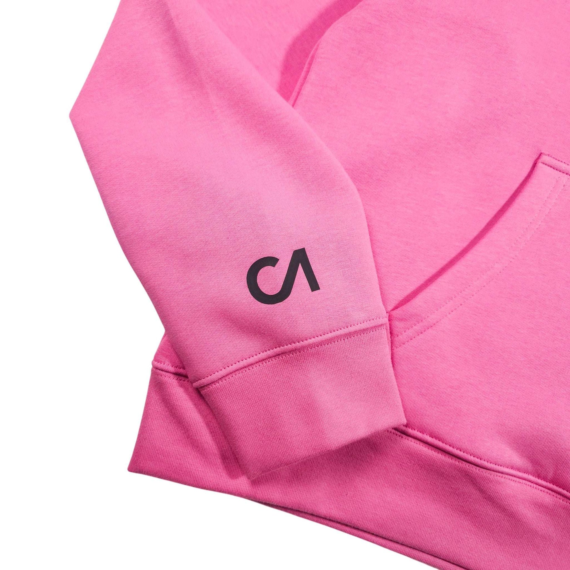 Pink hoodie sleeve with small black logo and ribbed cuffs, shown close-up