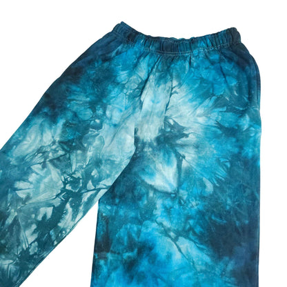 Blue tie-dye jogging bottoms, upper-leg view with elastic waistband and side seam