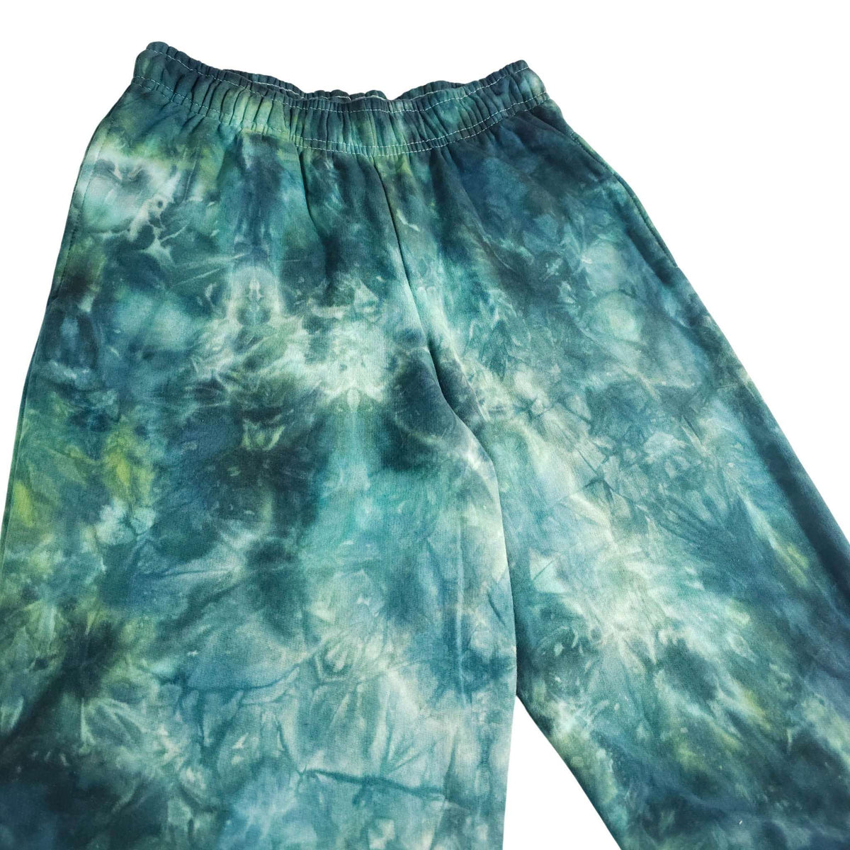 Teal and green tie-dye joggers close-up with elastic waistband and center seam detail.