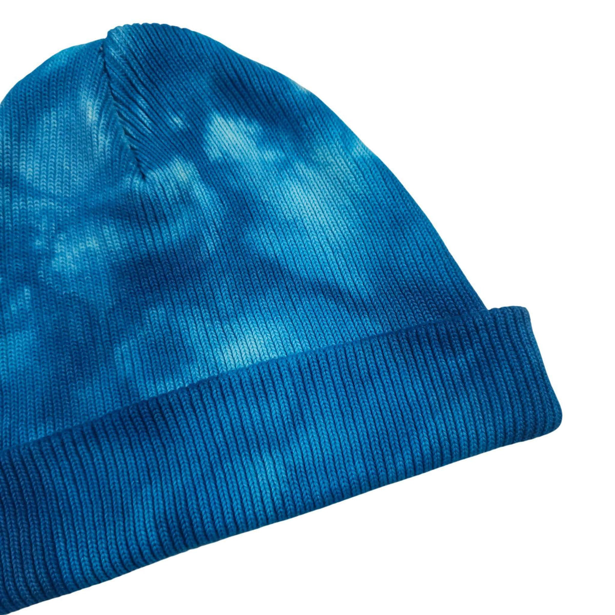 Blue knit beanie hat angled view with ribbed cuff and lighter tie-dye patches