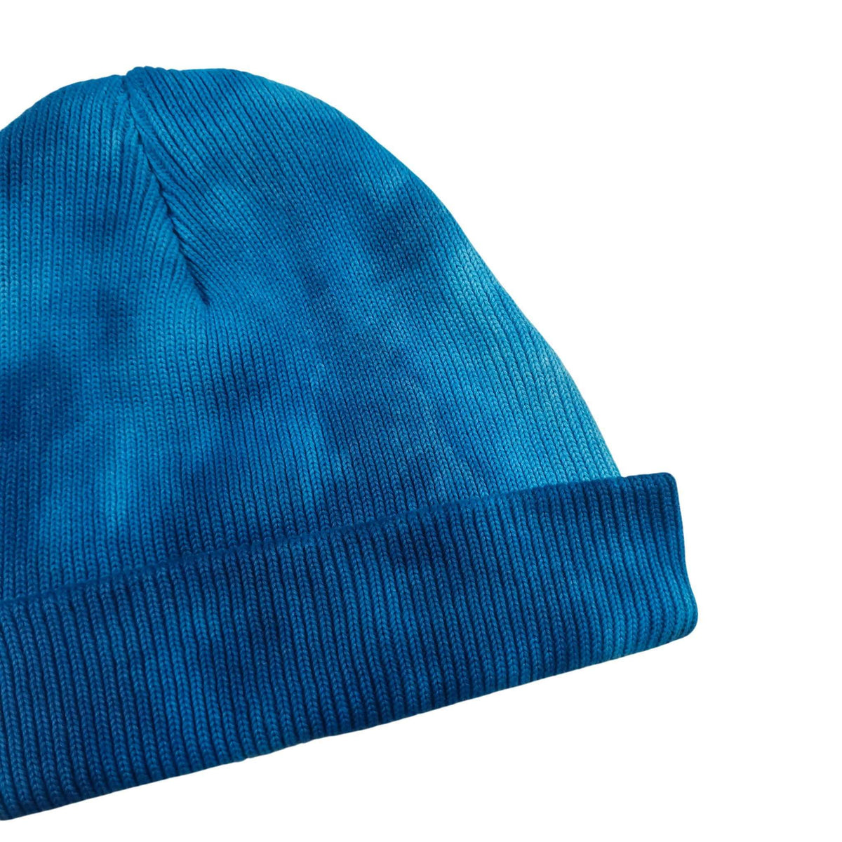 Blue knit beanie hat with ribbed cuff and lighter swirl patch at side