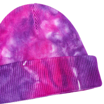 Tie-dye knit beanie with ribbed cuff, visible seam and folded edge in pink and purple