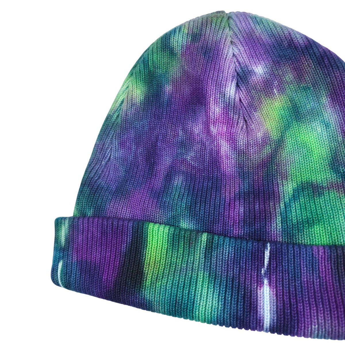 Tie-dye knit beanie hat showing curved crown and ribbed purple-green cuff