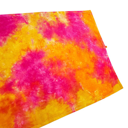 Folded tie-dye tea towel with pink and orange swirls, angled view