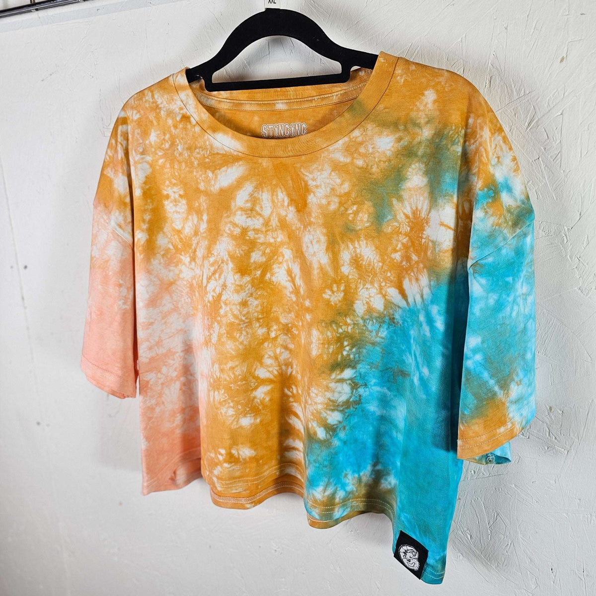 Orange, peach & blue tie-dye crop top on hanger, short sleeves and crew neck.