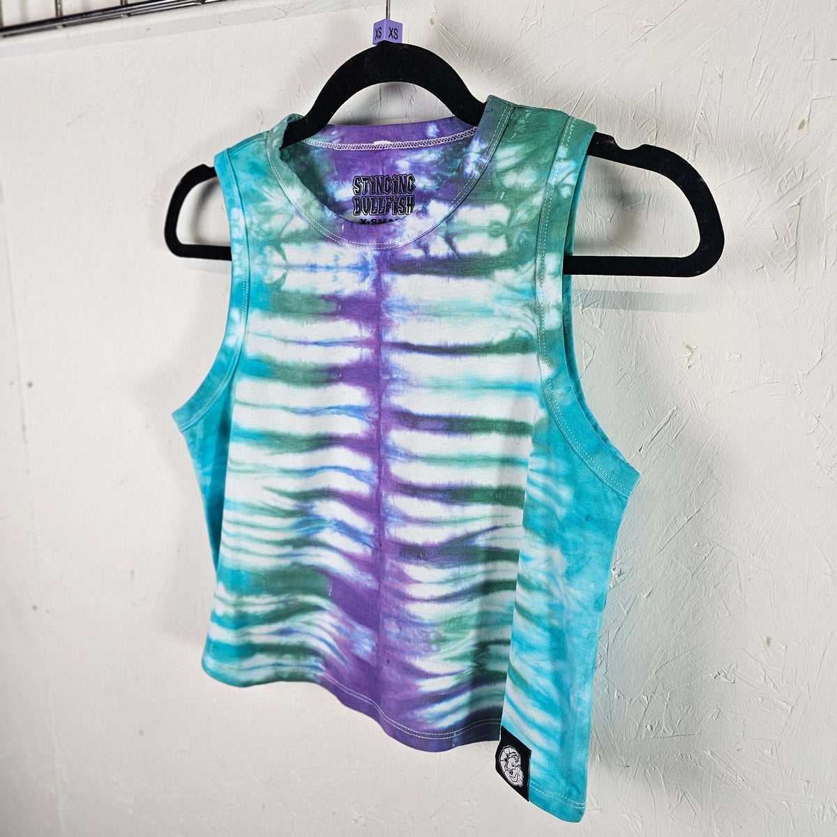 Tie-dye ribcage crop vest in teal and violet, sleeveless racerback with curved hem