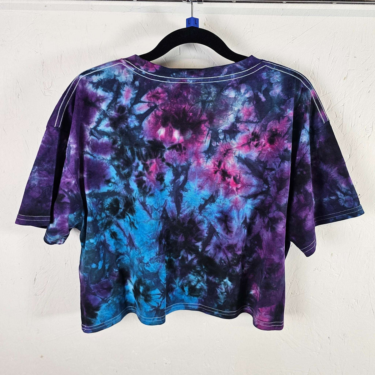 Back view of purple and blue tie-dye crop top with short sleeves and crew neck