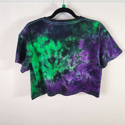 Back view of green and purple tie-dye crop top, short sleeves, crew neck, black hem trim