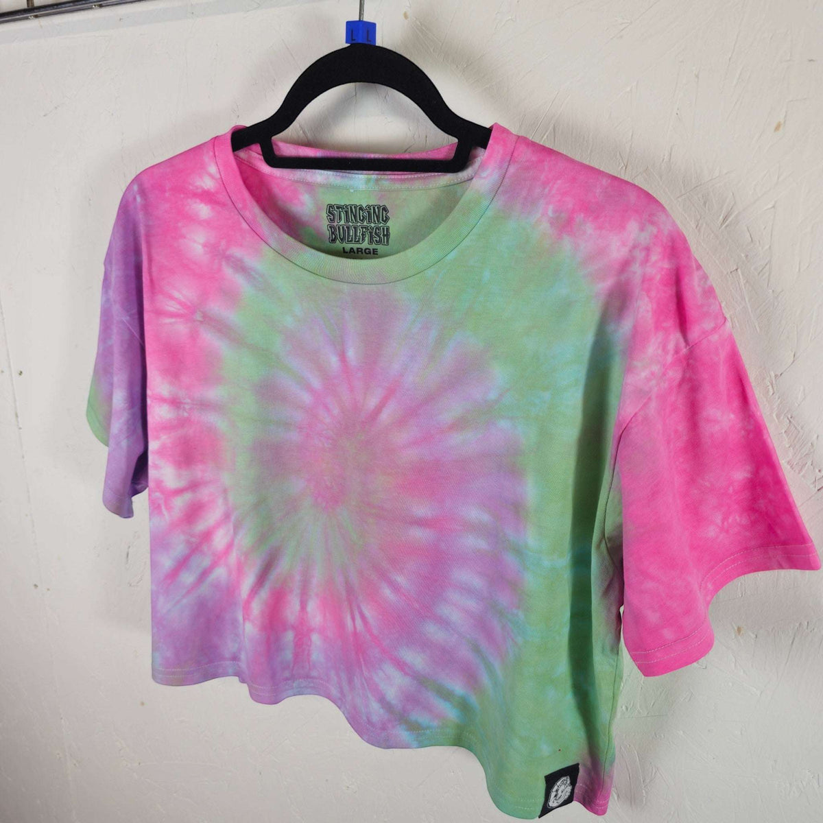 Pastel spiral tie-dye crop top with short sleeves and crew neck, angled view