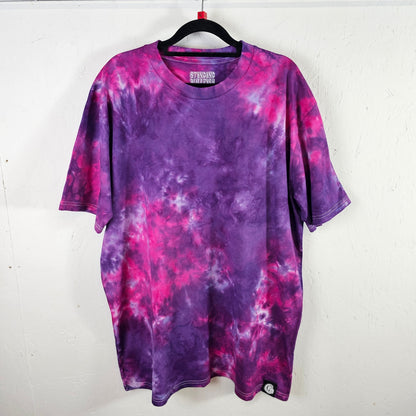 Purple and pink tie-dye t-shirt on a hanger against a white background
