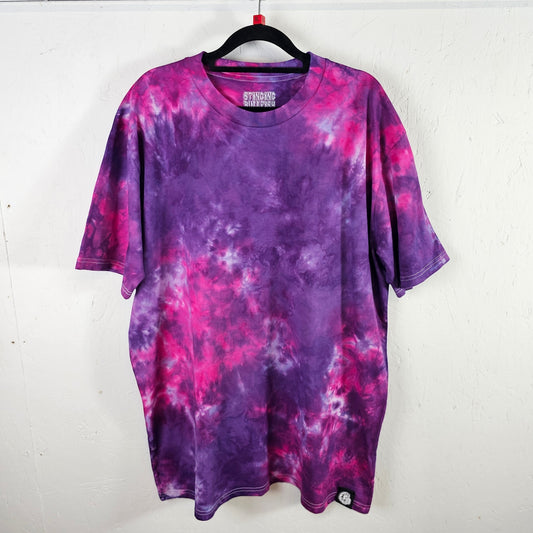 Purple and pink tie-dye t-shirt on a hanger against a white background