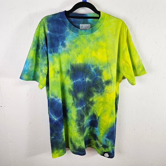 Tie-dye t-shirt with blue and green pattern on a hanger against a white background